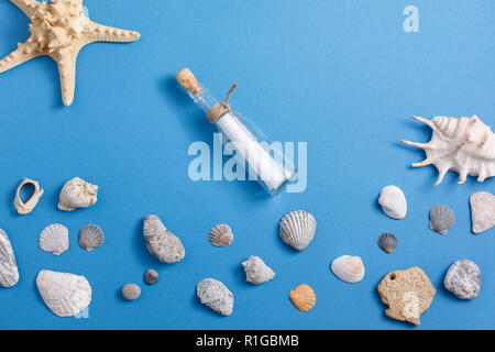 Les coquillages de mer et un message dans une bouteille sur fond bleu turquoise. Vue de dessus. Banque D'Images