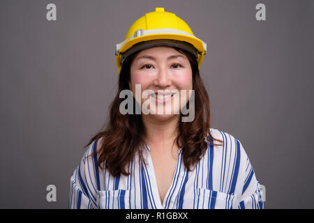 Mature Asian young construction worker wearing hardhat Banque D'Images