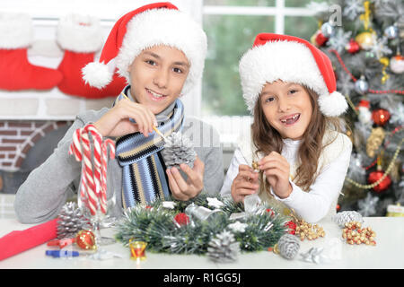 Happy brother and sister dans Santa hats prépare pour les fêtes de Noël Banque D'Images