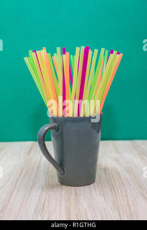 Une tasse en céramique gris rempli de pailles en plastique de plusieurs couleurs Banque D'Images