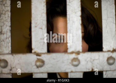 Portrait of a mid-adult business woman behind bars dans un bâtiment abandonné. Banque D'Images