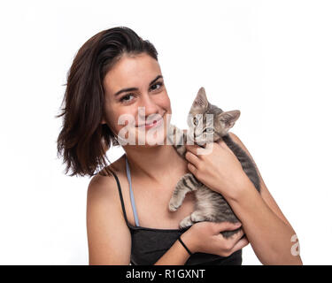 Adolescente et son adorable chaton tigré gris des pattes arrières avec sa main. Banque D'Images