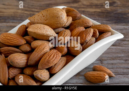 Bol d'amandes séchées rôti sur la vieille table en bois Banque D'Images
