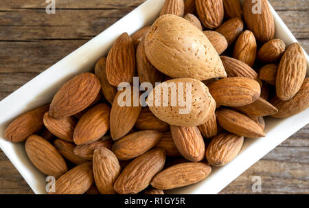 Bol d'amandes séchées rôti sur la vieille table en bois Banque D'Images