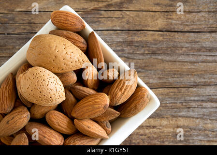 Bol d'amandes séchées rôti sur la vieille table en bois Banque D'Images