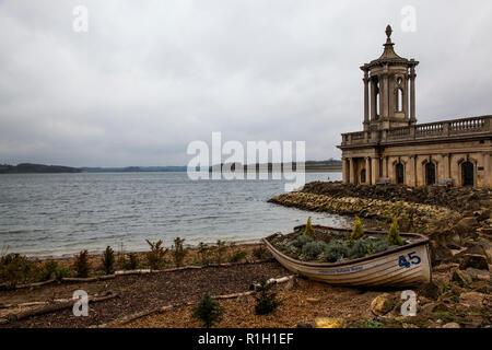 Le 19ème siècle en partie submergé l'église St Matthieu à Normanton dépasse sur Rutland Water, aux côtés d'un vieux bateau à rames. Banque D'Images