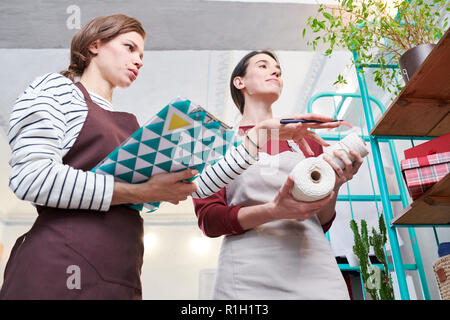Vue de côté portrait de deux jeunes femmes portant des tabliers de travail shop le décorer pour Noël Banque D'Images