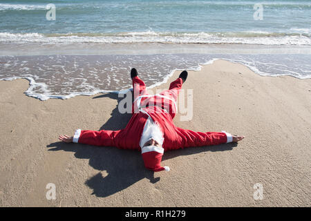 Santa Claus vues de face sur le sable d'une plage, avec la mer en arrière-plan Banque D'Images