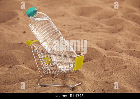 Panier miniature avec bouteille en plastique avec de l'eau laissée par touriste sur une plage tropicale. L'eau est un produit vendable la pollution de l'environnement. Con Banque D'Images