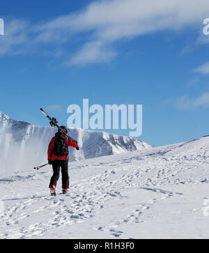 Avec skieur skis sur l'épaule aller jusqu'en haut de la montagne dans le froid soleil jour. Hiver montagnes du Caucase, la Géorgie, la région Gudauri, Mt. Kudebi. Banque D'Images