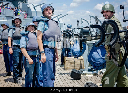 Membres de l'USS Alabama's Living History Crew regarder une foule se presse pour les voir s'engager dans une simulation d'avions de la Seconde Guerre mondiale bataille. Banque D'Images