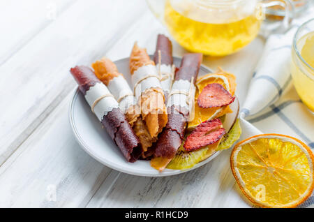 De nombreux fruits divers rouleaux de cuir et de plaquettes et de verre tasse théière et de l'argousier plateau sur le petit déjeuner sur la table en bois blanc, lumière naturelle, selektive Banque D'Images