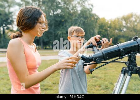 Adolescents Enfants avec Hubble regardez le ciel dans la nature. Banque D'Images