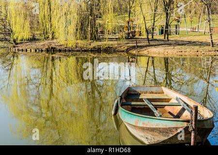 Belle image d'un lac au milieu d'un parc avec un petit bateau ancré sur la rive, entourée d'arbres sur une magnifique journée Banque D'Images