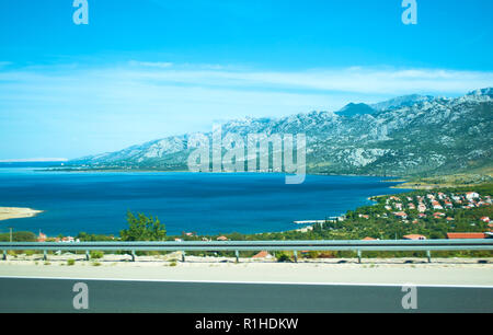 Sur la route de l'arrière-plan de montagnes Velebit, petites maisons parmi les arbres verts et mer bleu azur de l'eau sur une journée d'été. La Croatie Banque D'Images