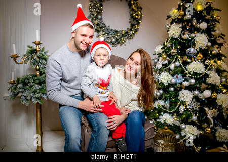 Famille heureuse, père, mère et fils, le matin dans la salle de séjour décorée pour Noël. Ils ouvrent des cadeaux et s'amuser. La nouvelle année et thème de Noël. Ambiance de vacances Banque D'Images