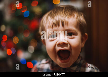 Cheerful baby boy avec bouche ouverte jouant à la maison durant les vacances de Noël Banque D'Images