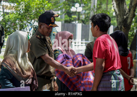 Agent de la Police de la charia islamique (Wilayatul Hisbah) vu serrant la main d'un homme portant un sarong au cours de la routine des raids dans la ville de Lhokseumawe. Les agents de la Police de la charia islamique (Wilayatul Hisbah) fournir des sarongs pour ceux qui violent la loi de la charia islamique par la force dans la ville de Lhokseumawe, Aceh est la seule province de l'Indonésie qui a la plus grande population de musulmans dans le monde, qui met en œuvre la charia islamique comme la commission de la bastonnade et mener des raids de routine pour ceux qui sont bien habillés pour femmes et des shorts pour hommes. Banque D'Images