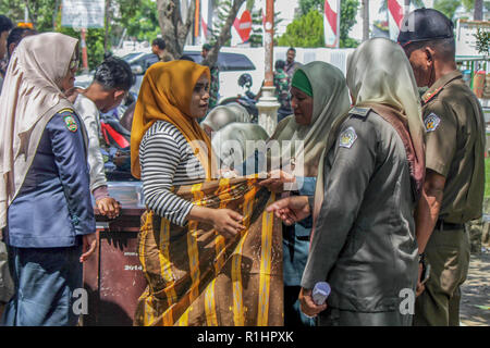 Agent de la Police de la charia islamique (Wilayatul Hisbah) est vu attacher un sarong pour une femme qui a violé la loi de la charia islamique par la force dans la ville de Lhokseumawe. Les agents de la Police de la charia islamique (Wilayatul Hisbah) fournir des sarongs pour ceux qui violent la loi de la charia islamique par la force dans la ville de Lhokseumawe, Aceh est la seule province de l'Indonésie qui a la plus grande population de musulmans dans le monde, qui met en œuvre la charia islamique comme la commission de la bastonnade et mener des raids de routine pour ceux qui sont bien habillés pour femmes et des shorts pour hommes. Banque D'Images