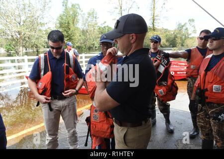 Rép. américain Brian Mât, R-Palm City, Floride, lui met un gilet avant une évaluation de la Garde côtière de Oak Grove, North Carolina, quartiers inondées par l'ouragan Florence, le 20 septembre 2018. L'air et de la surface de la Garde côtière canadienne a sauvé 1 103 personnes d'équipage et 419 animaux domestiques depuis l'ouragan Florence) a frappé le 14 septembre 2018. Banque D'Images