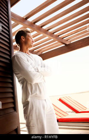 Mi-contemplative des profils homme debout, les bras croisés sur le patio d'un beach resort. Banque D'Images