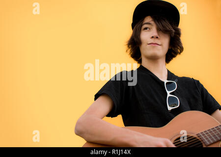 Portrait d'un jeune garçon portant un chapeau et posant avec sa guitare. Banque D'Images