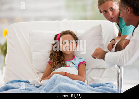 Jeune fille dans un lit d'hôpital, parler avec son médecin et l'infirmière. Banque D'Images