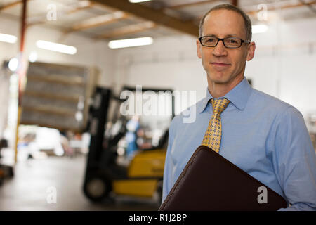 Portrait of a young businessman standing dans une usine. Banque D'Images