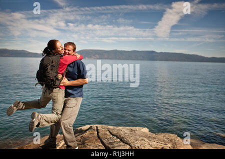 Mid-adult woman hugging excité son mec à côté de lac magnifique. Banque D'Images