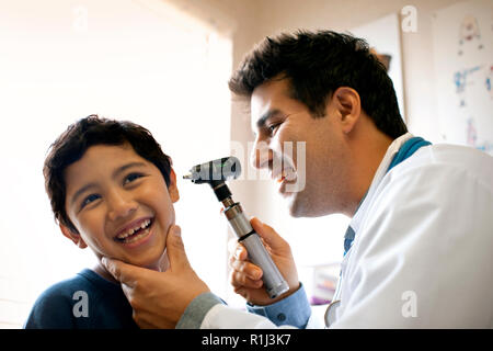 Médecin examinant son jeune patient's ear avec un otoscope. Banque D'Images