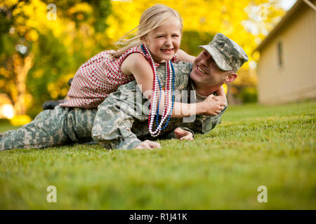 Soldat mâle et sa jeune fille jouant sur la pelouse dans leur cour arrière. Banque D'Images