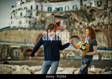 Heureux couple d'âge moyen heureusement se promener le long de la côte. Banque D'Images