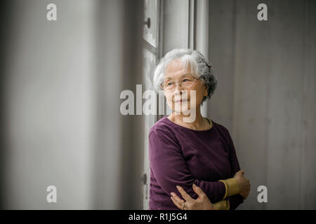 Portrait of a smiling woman regarder par la fenêtre. Banque D'Images