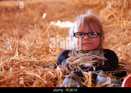 Petite fille portant sur un tas de foin Banque D'Images