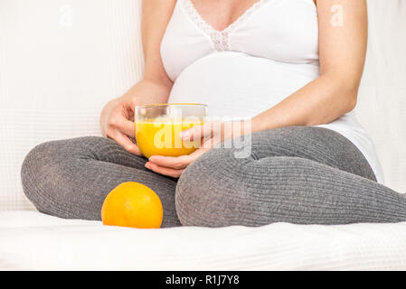 Pregnant woman holding a mug avec du jus d'orange Banque D'Images