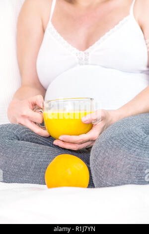 Pregnant woman holding a mug avec du jus d'orange Banque D'Images