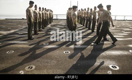 Golfe d'ADEN - U.S. Marine Cpl. Diego Carroll, ingénieur de combat avec la compagnie Kilo, bataillon de l'équipe d'atterrissage 3/1, 13e Marine Expeditionary Unit (MEU), les promenades le long de son peloton pendant une inspection uniforme pour le caporal's Course à bord de la classe Whidbey Island landing ship dock USS Rushmore (LSD 47), le 6 octobre 2018. Le groupe amphibie d'Essex et la 13e MEU sont déployés dans le domaine de la 5e flotte américaine des opérations à l'appui des opérations navales pour assurer la stabilité et la sécurité maritime dans la région Centrale, reliant la Méditerranée et le Pacifique à travers l'ouest de l'Océan indien et trois s Banque D'Images