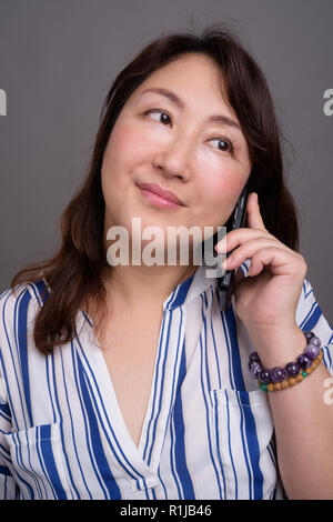 Belle asiatique mature businesswoman talking on phone Banque D'Images