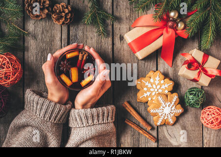 Portrait of woman holding glass avec vin chaud sur fond de bois avec des cadeaux de Noël Banque D'Images