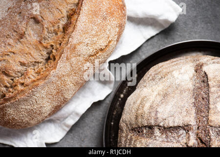 Vue de dessus de loafs sur pain frais sur le linge et la plaque sur la surface gris Banque D'Images