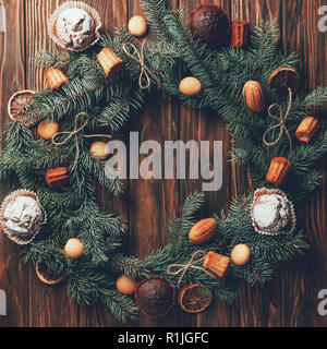 Vue de dessus de couronne de sapin avec de délicieux petits gâteaux et muffins sur la table en bois, concept de Noël Banque D'Images