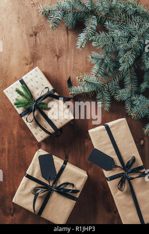 Vue de dessus de cadeaux de Noël avec des branches de sapin et de tags sur fond de bois Banque D'Images