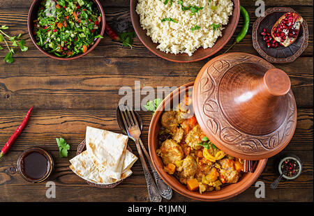 Tajine, couscous plats traditionnels et salade fraîche sur table en bois rustique. Tagine d'agneau et de potiron. Vue d'en haut. Mise à plat Banque D'Images