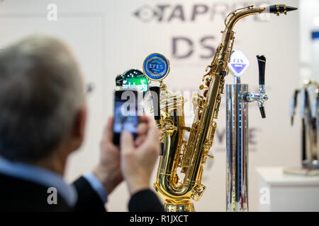 Nuremberg, Allemagne. 13 novembre, 2018. Au BrauBeviale boissons juste, un visiteur prend une photo d'un système de distribution sous la forme d'un saxophone sur le stand de l'entreprise néerlandaise Aalberts en utilisant son téléphone mobile. Photo : Daniel Karmann/dpa dpa : Crédit photo alliance/Alamy Live News Banque D'Images
