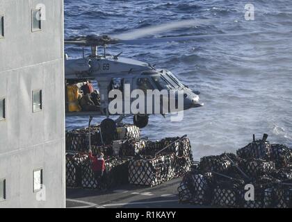 L'OCÉAN PACIFIQUE (oct. 12, 2018) Un membre de l'équipe de reconstitution de la flotte oiler USNS Guadalupe (T-AO 200) se fixe à un cargo Sea Hawk MH-60S affecté à la "Jokers" de la mer d'hélicoptères de combat (HSC) Squadron 23 en transit vers le poste de pilotage de navire d'assaut amphibie USS Boxer (DG 4) au cours d'un ravitaillement en mer. Boxer est en cours la réalisation des opérations de routine dans la 3ème zone d'opérations de la flotte. Banque D'Images