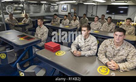 La mer d'OMAN - Marines des États-Unis avec la 13e Marine Expeditionary Unit (MEU), d'écouter l'intervenant au cours d'un diplôme de fin de l'Art Martial - instructeur à bord de la classe Whidbey Island landing ship dock USS Rushmore (LSD 47), 12 octobre, 2018. Le groupe amphibie d'Essex et la 13e MEU sont déployés dans le domaine de la 5e flotte américaine des opérations à l'appui des opérations navales pour assurer la stabilité et la sécurité maritime dans la région Centrale, reliant la Méditerranée et le Pacifique à travers l'ouest de l'Océan indien et trois points d'étranglement stratégiques. Banque D'Images