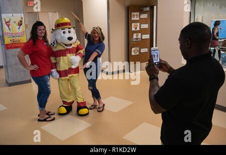 U.S. Air Force Tech. Le Sgt. Boykins Marshall, 18e Escadron de génie civil sous-officier responsable des inspections de prévention des incendies, prend une photo de Lacey Holmstrom, gauche, vice-président de l'Organisation des parents et des enseignants, Sparky le chien de feu et Jennifer Fontaine, président de la PDF, 10 octobre 2018, à l'école elementry Kadena sur Kadena Air Base, au Japon. La campagne de cette année pour la Semaine de la prévention des incendies est "l'aspect. Écouter. En savoir. Être au courant, le feu peut se produire n'importe où." La campagne est axée sur l'éducation sur la façon dont ils peuvent réduire la probabilité d'avoir un feu et à s'échapper en toute sécurité pendant un incendie. Banque D'Images