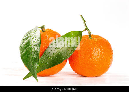 Mandarines avec feuilles et gouttes d'eau sur fond de bois blanc, gros plan Banque D'Images