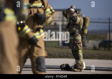 Un pompier de l'armée de l'air liens familiaux ses cheveux jusqu'après avoir participé à une simulation des forces aériennes américaines au cours d'une Europe en cours de l'OTAN Partenariat pompier sur la base aérienne de Ramstein, en Allemagne, le 10 octobre 2018. Cette formation renforce l'interopérabilité avec les alliés de l'OTAN et s'assure que toutes les forces sont qualifiés, formés et compétents, le personnel de sauvetage. Banque D'Images