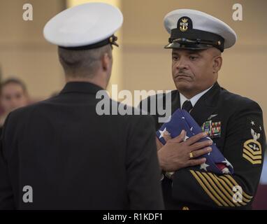 Grands Lacs, Illinois (oct. 12, 2018) Maître Chef d'Ordnanceman Aviation Oliver Brown détient l'enseigne pendant un passage de la cérémonie des drapeaux lors de sa retraite cérémonie à la commande d'entraînement des recrues. Brown prend sa retraite après 30 années de service naval. Plus de 30 000 recrues par année d'études supérieures de la marine est que boot camp. Banque D'Images